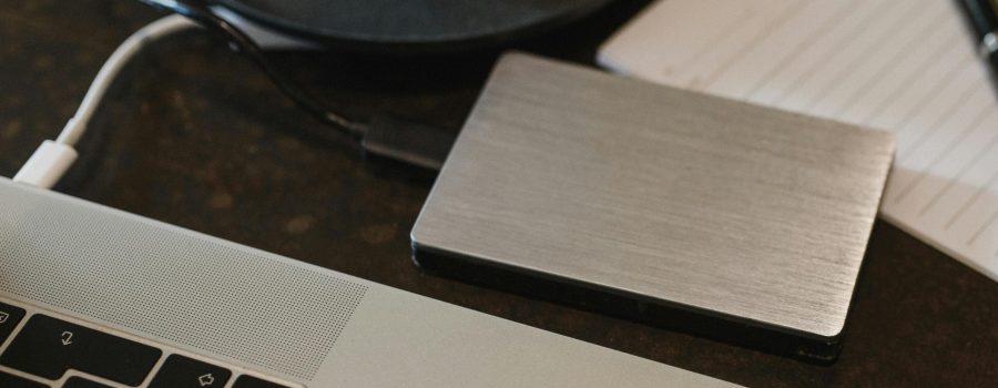 Free Closeup of an external hard drive connected to a laptop with a USB cable on a desk. Stock Photo